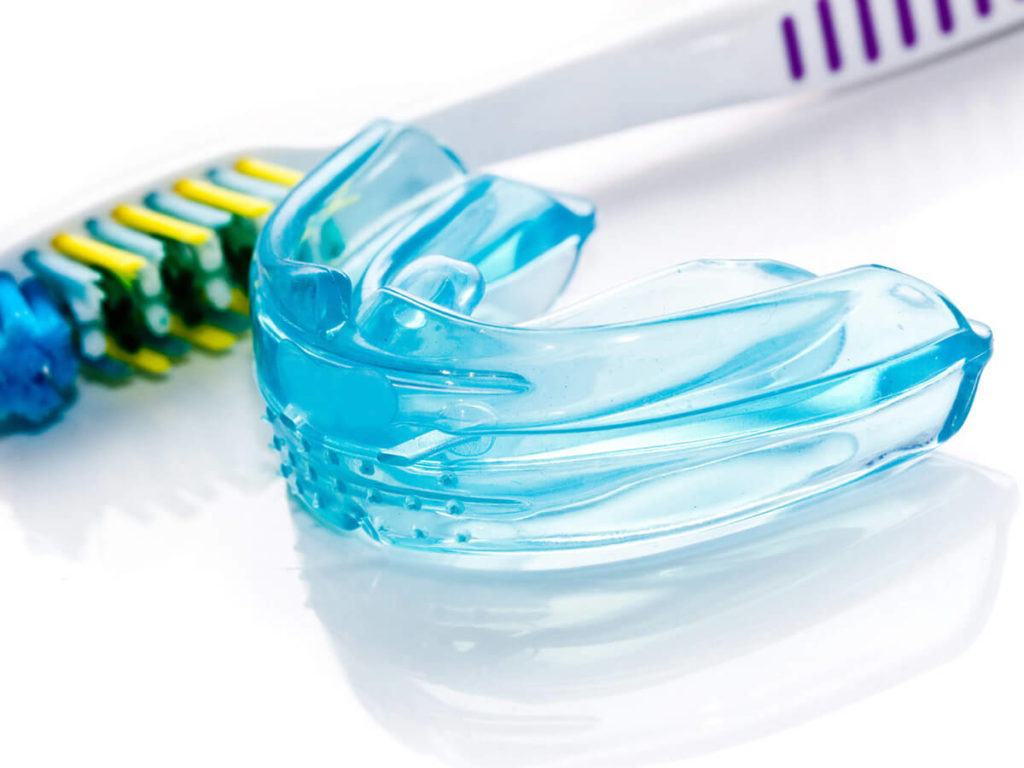 mouthguard and toothbrush next to one another