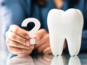 image of a person holding a question mark next to a fake tooth