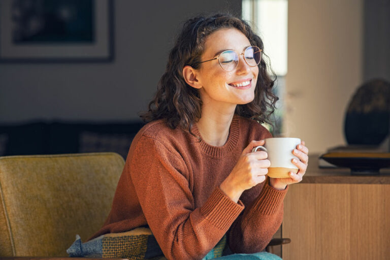 girl smiling and holding a cup of coffee