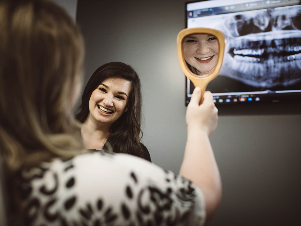 a girl holding up a mirror and smiling