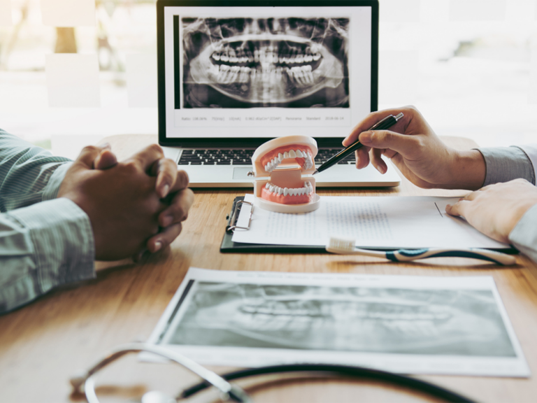 image of a person pointing a pen at a pair of fake teeth