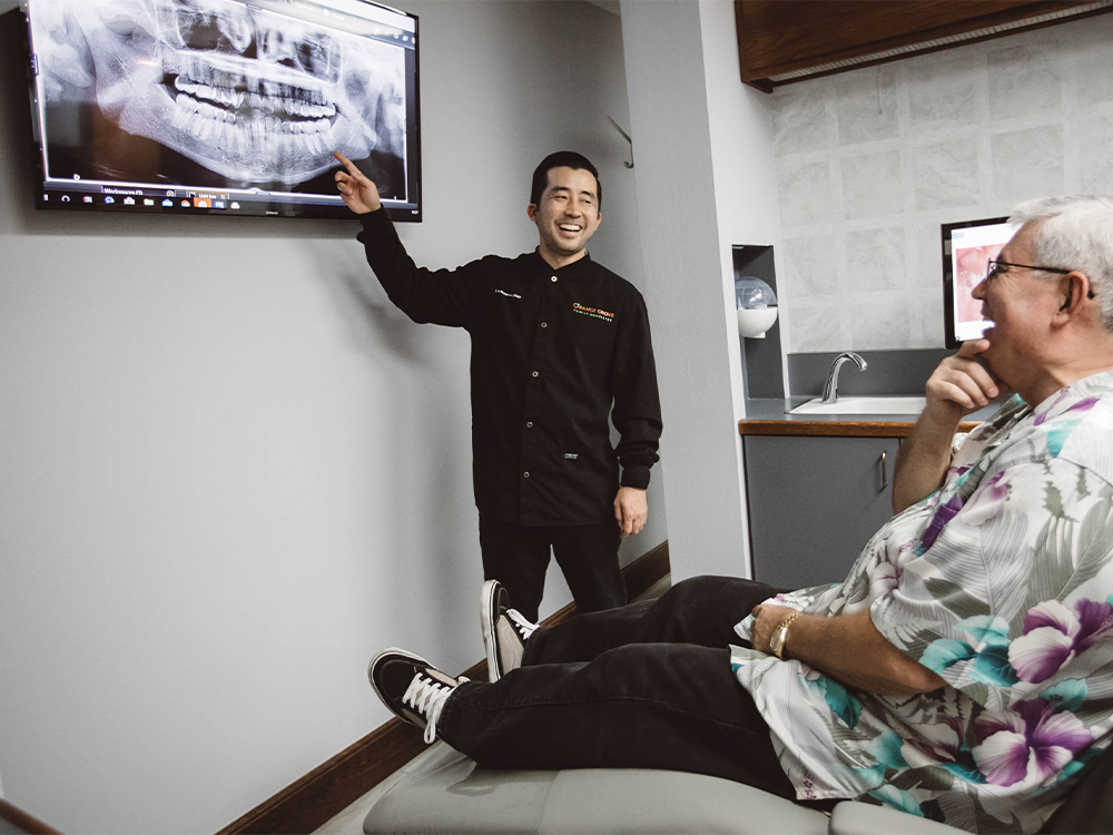 dr nishimura pointing at a dental x-ray in front of a patient