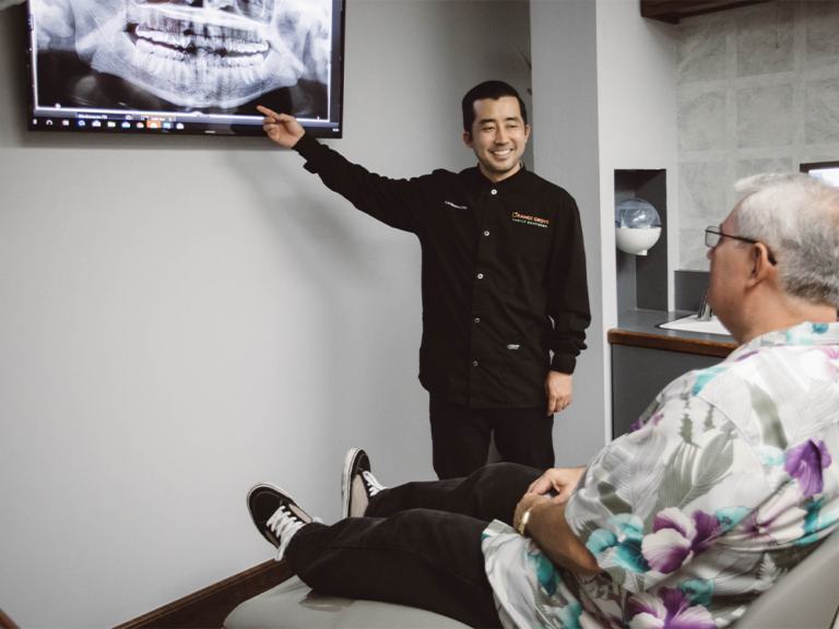 dr nishimura pointing at a dental scan in front of dental patient