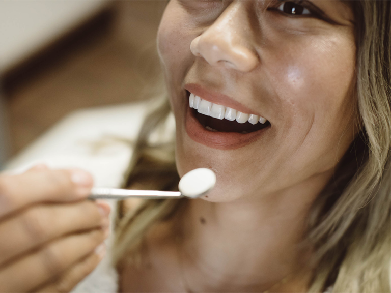 image of a girl smiling with a dental mirror near her mouth